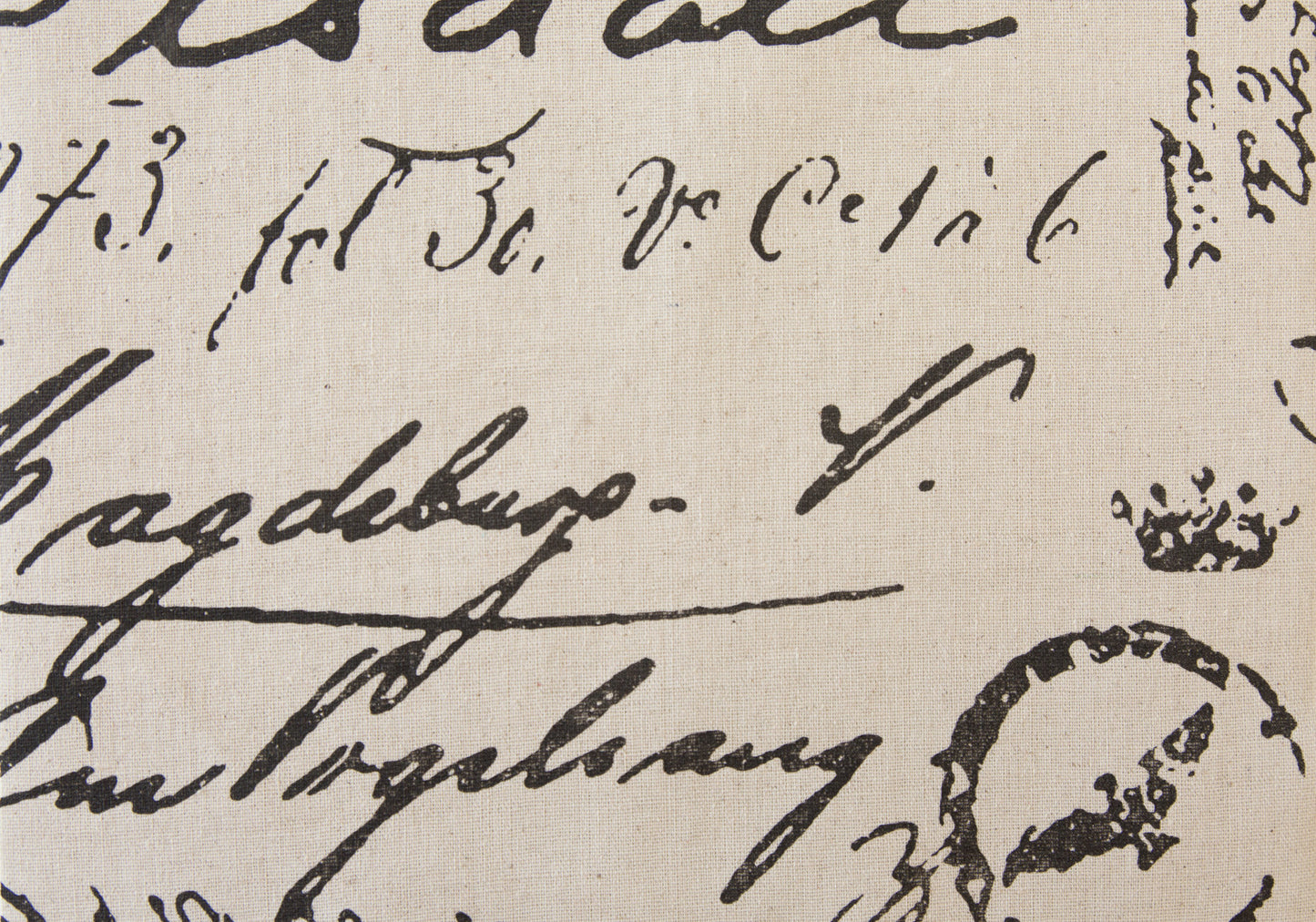 Closeup of vintage script fabric with black cursive lettering on natural linen