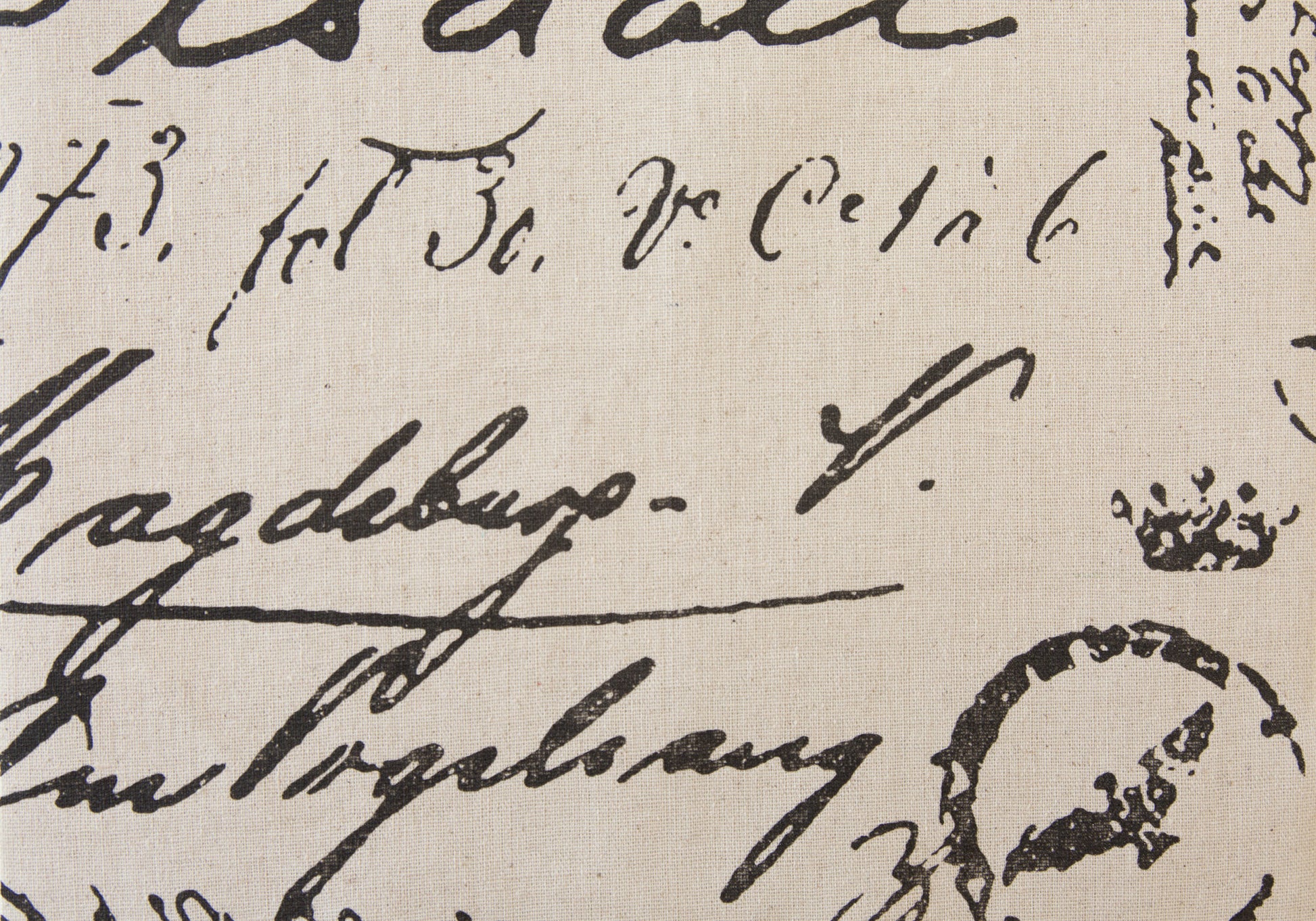 Closeup of vintage script fabric with black cursive lettering on natural linen
