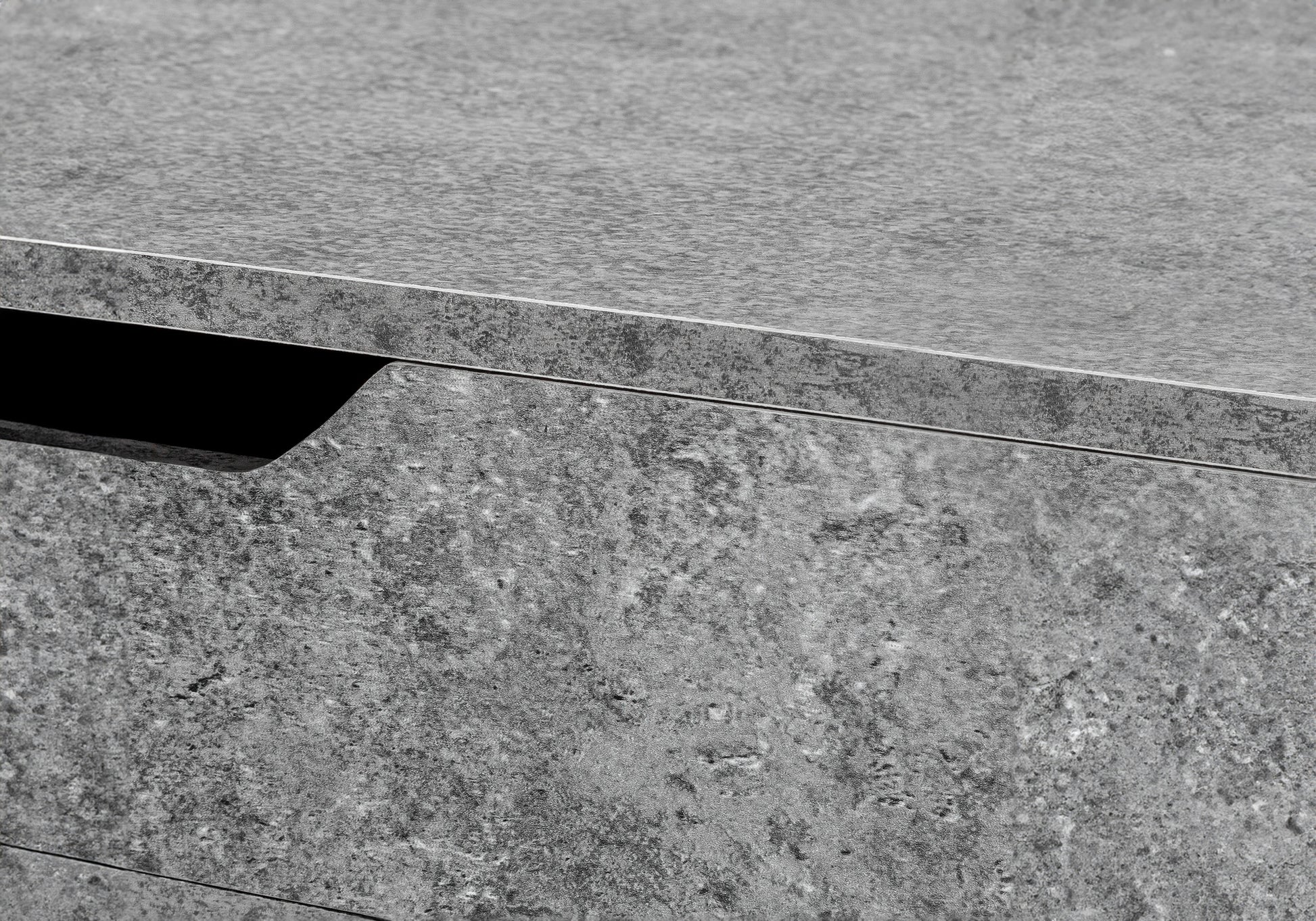 Closeup of textured gray concrete drawer front with integrated handle recess