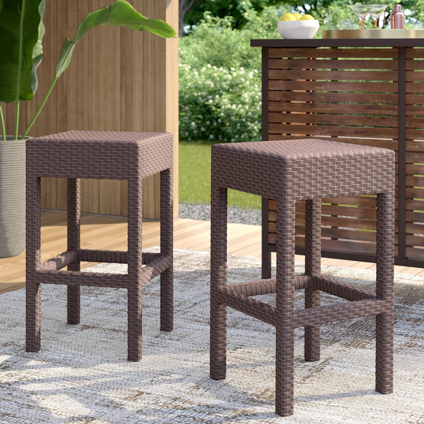Pair of brown wicker bar stools with square seats and open leg frames on outdoor patio rug