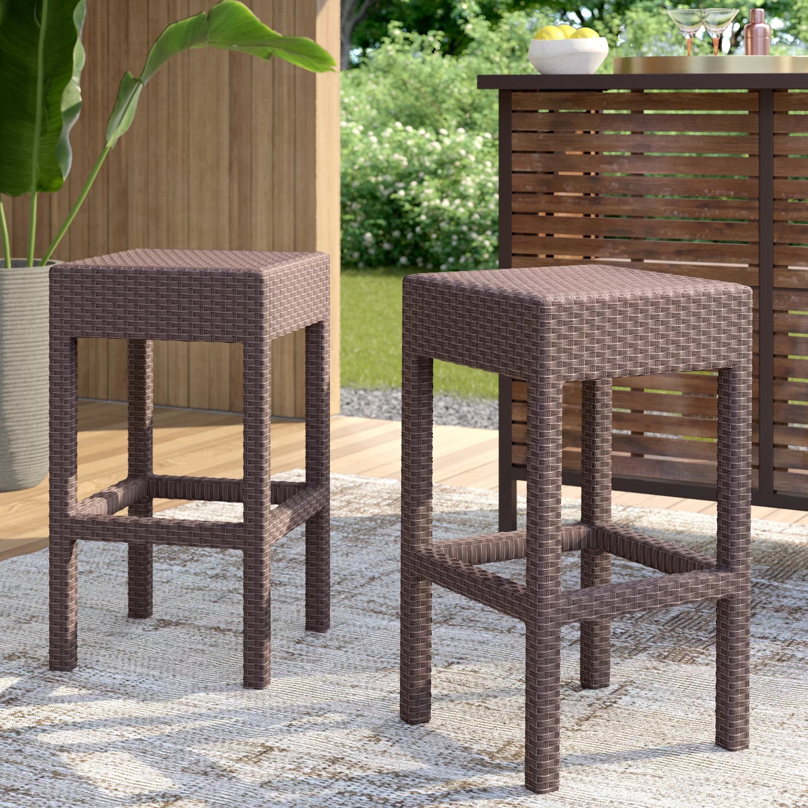 Pair of brown wicker bar stools with square seats and open leg frames on outdoor patio rug