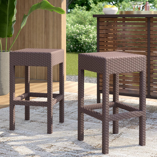 Pair of brown wicker bar stools with square seats and open leg frames on outdoor patio rug