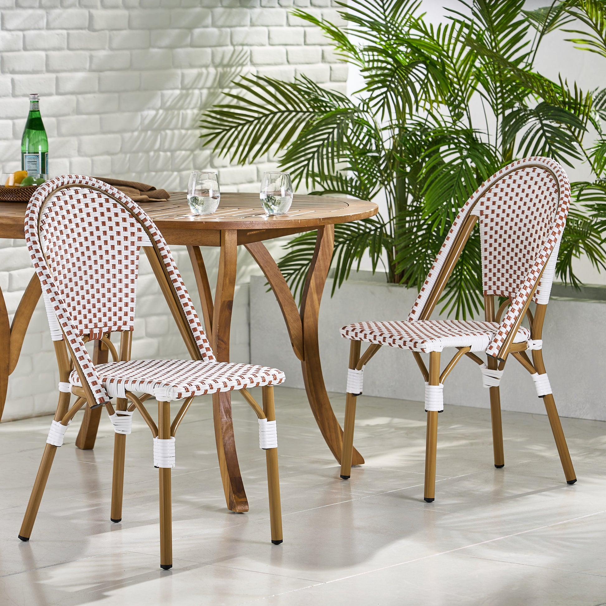 Two white and brown rattan bistro chairs at a round wooden table with two glasses of water