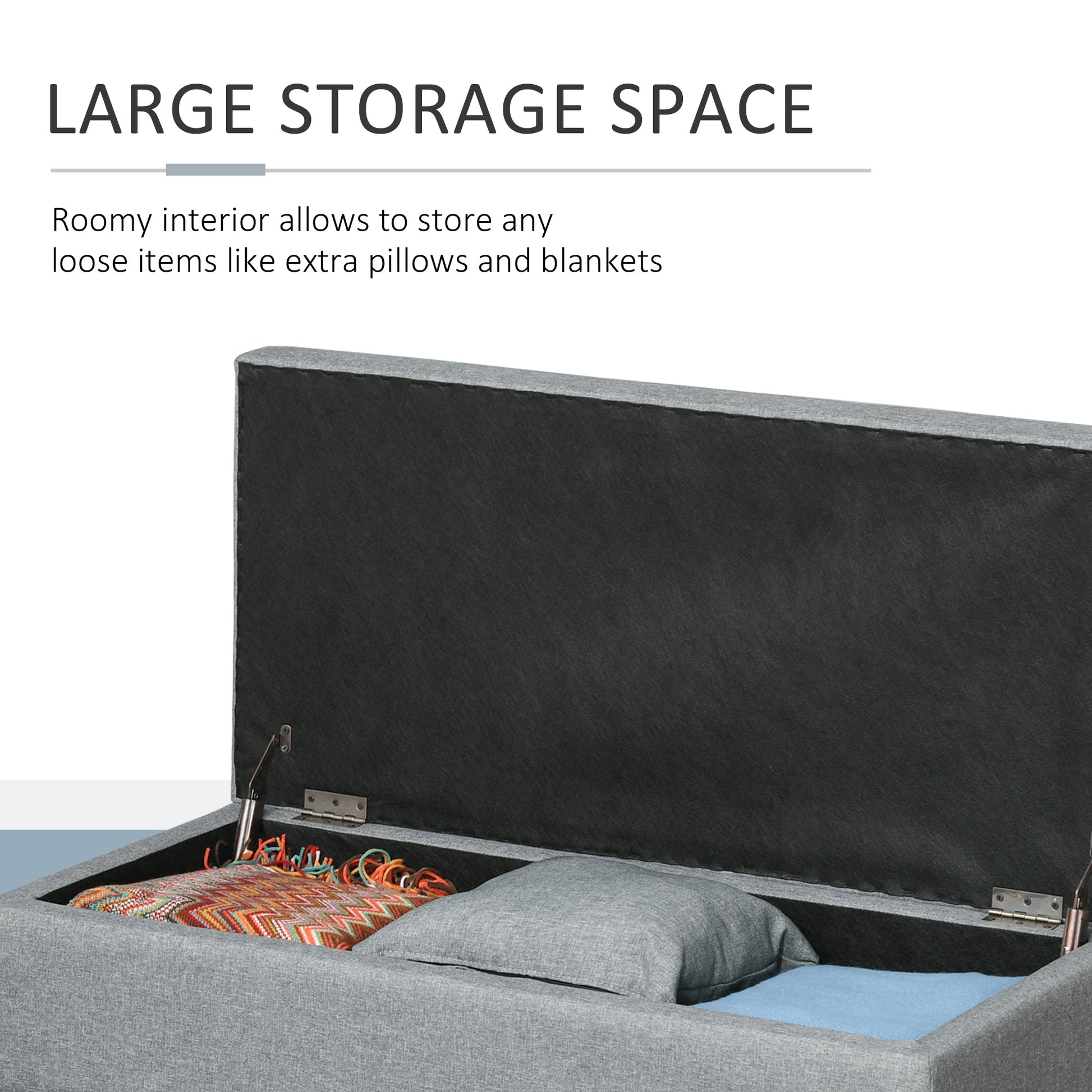 Gray fabric storage ottoman with lid open revealing blankets and pillow inside