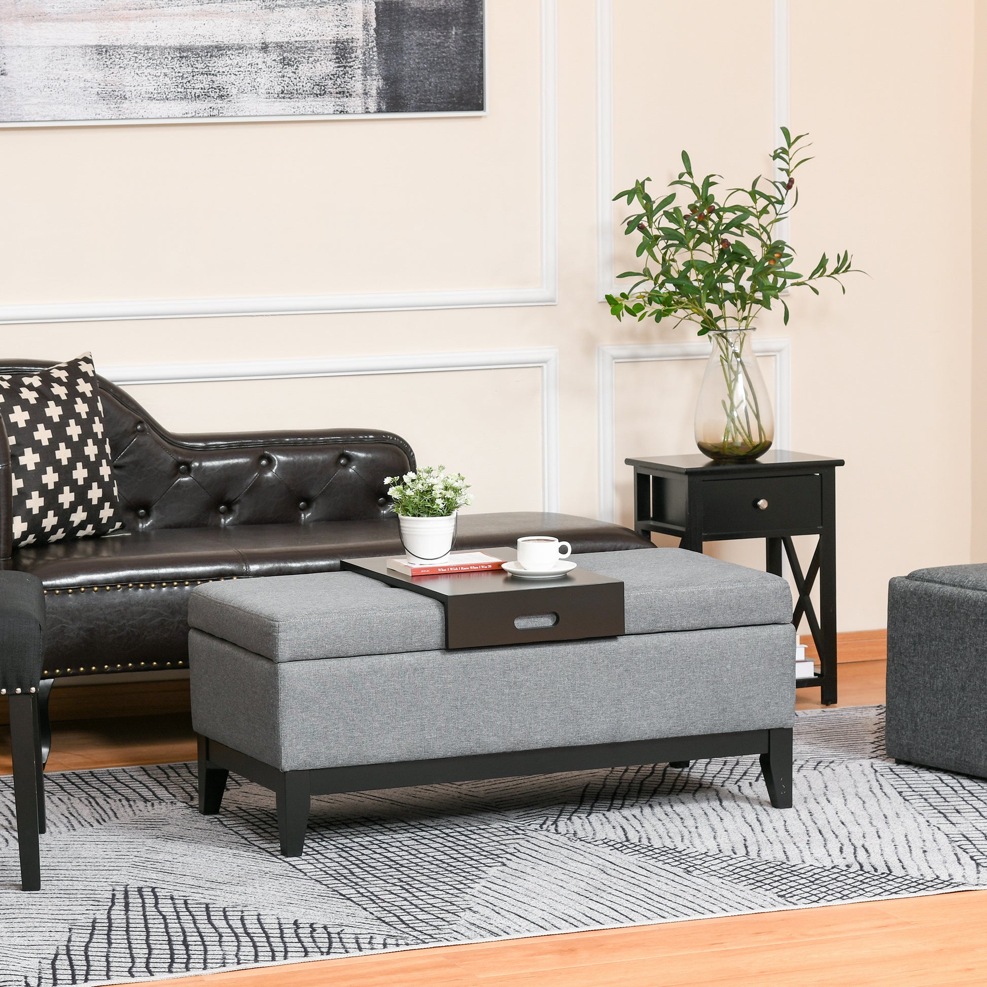 Grey fabric storage ottoman with a dark wood tray and white mug