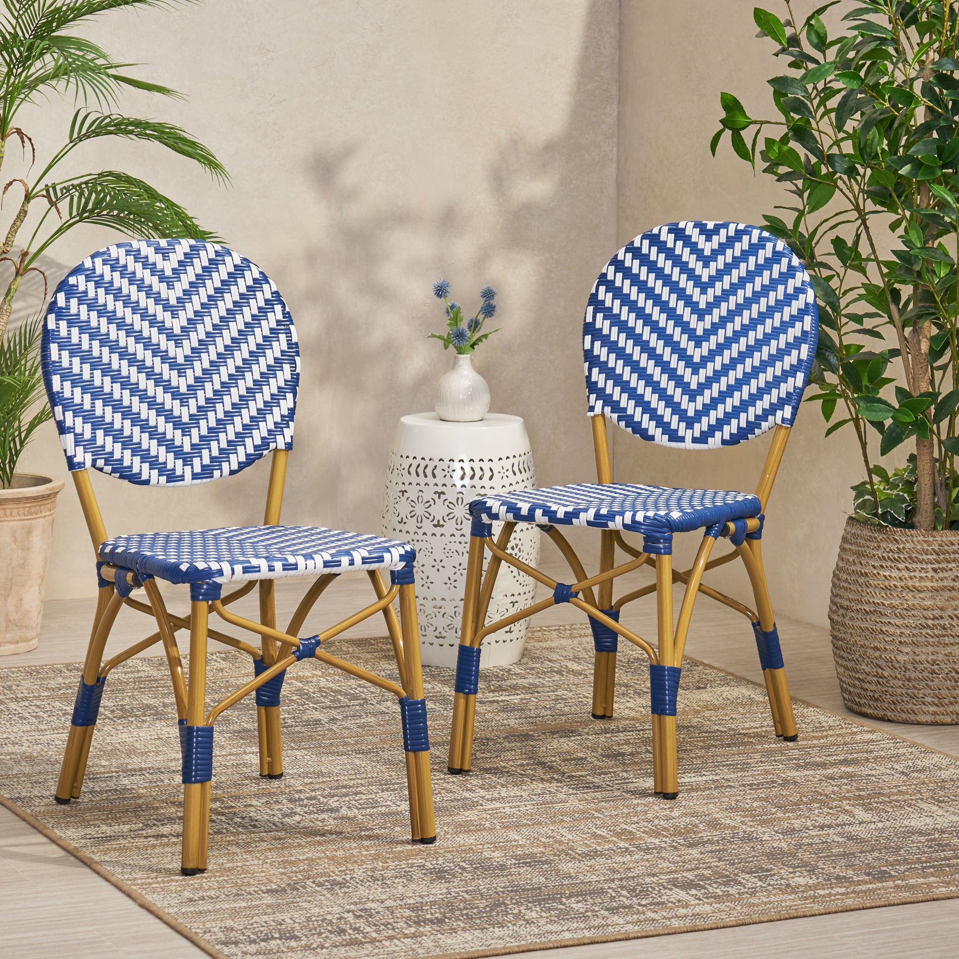 Two blue and white wicker bistro chairs with gold metal legs perfect for outdoor seating