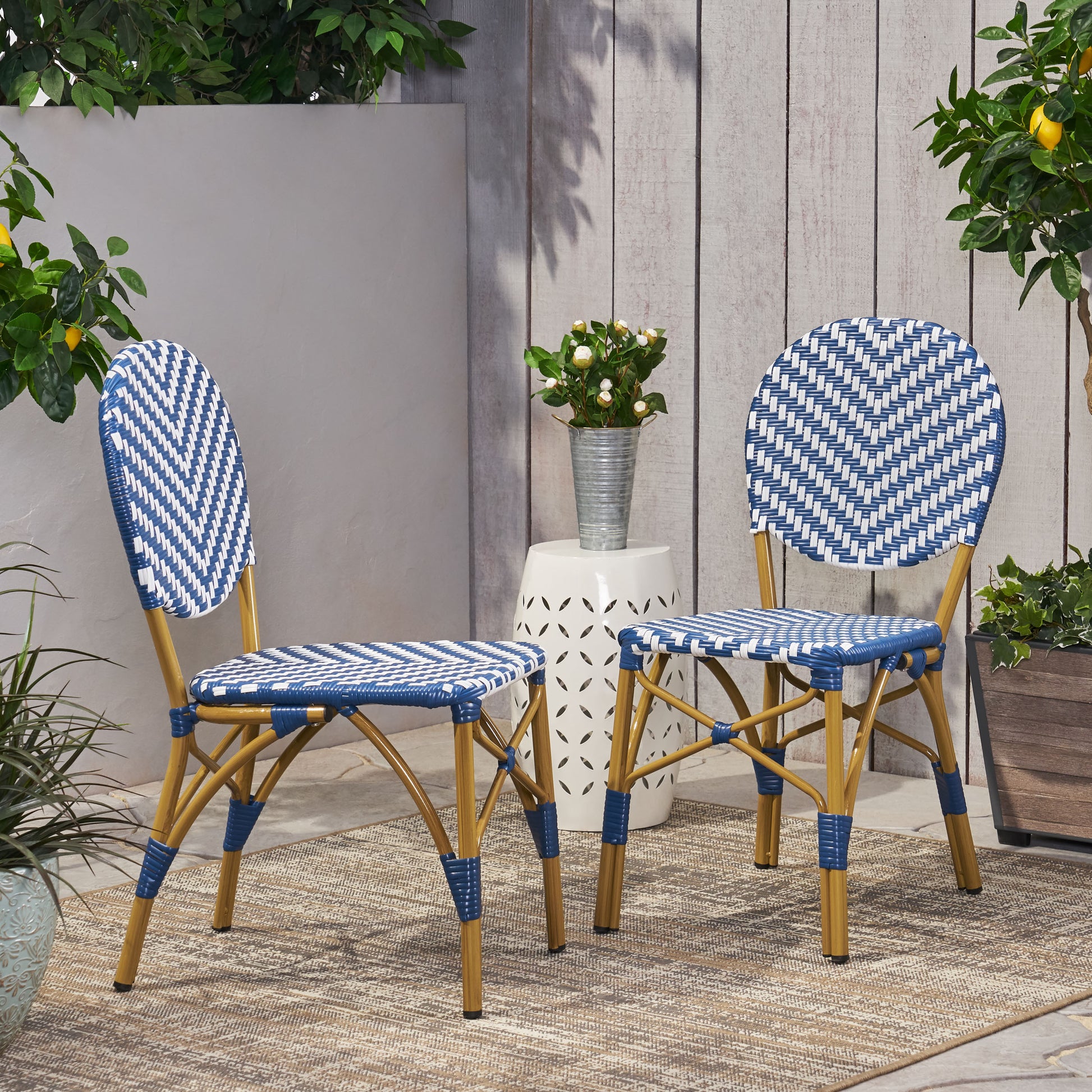 Two blue and white woven bistro chairs with rattan legs on an outdoor patio rug