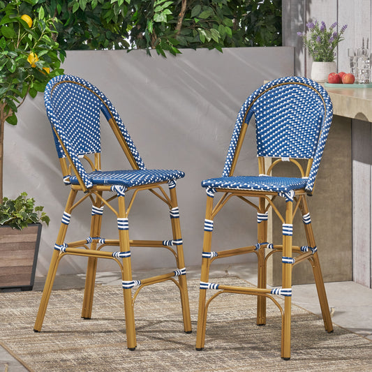 Two blue and white rattan bistro bar stools with gold metal frames on an outdoor patio