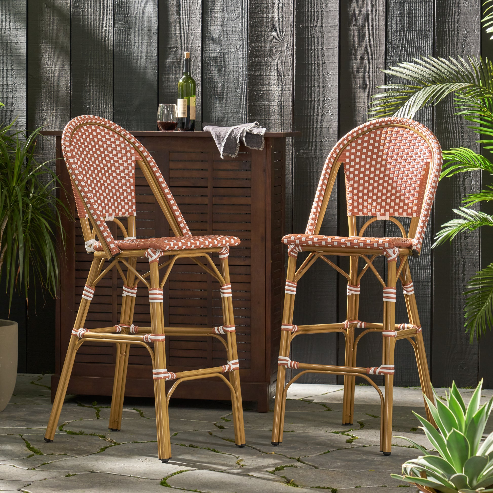Two terra cotta and white rattan bar stools with curved backs for outdoor seating