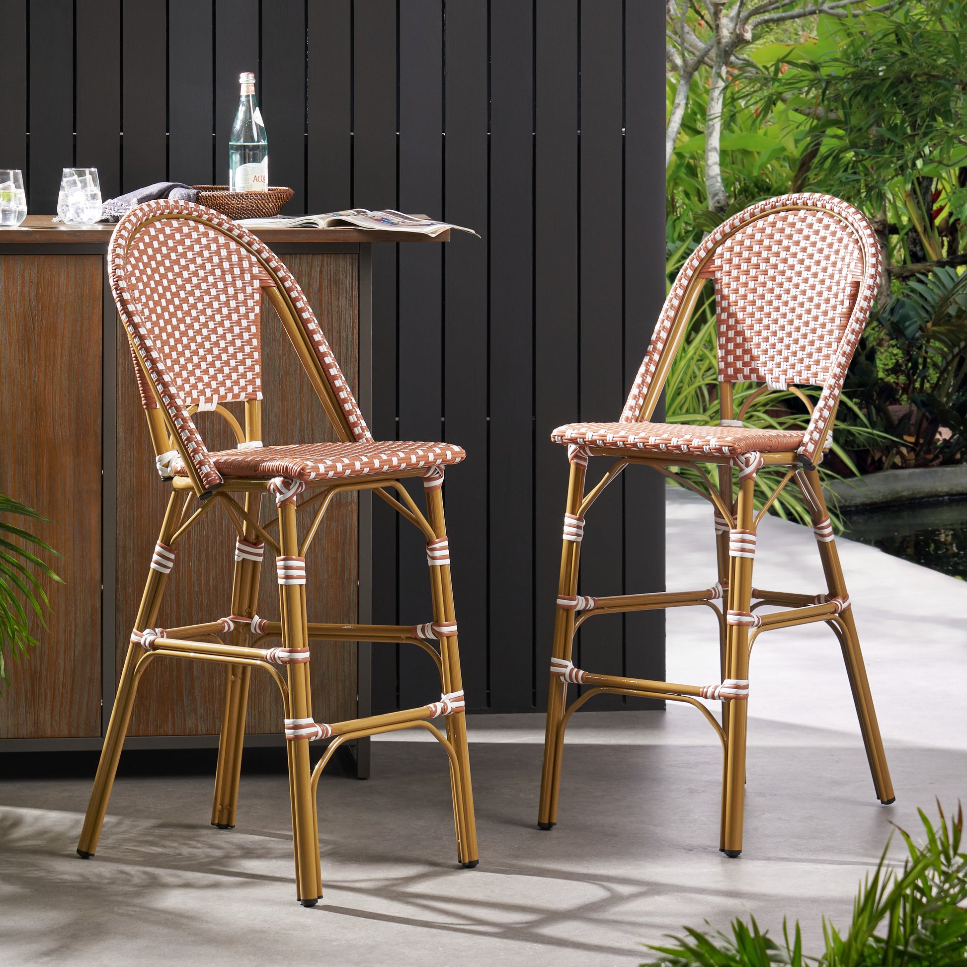 Two rattan bar stools with gold frames and woven brown and white seats perfect for outdoor patio seating