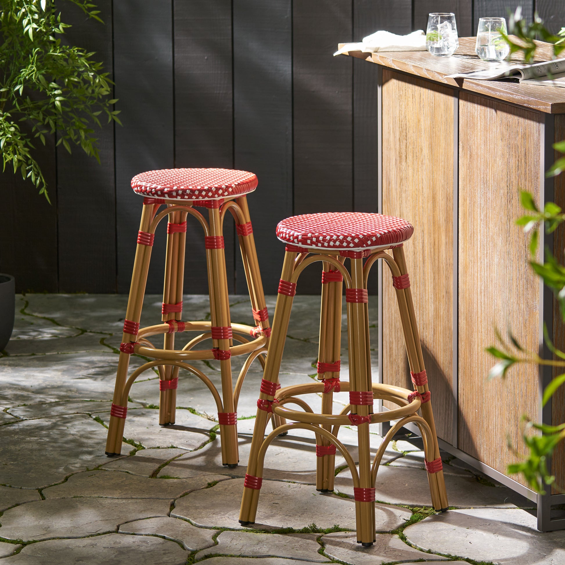 Two natural rattan bar stools with red and white checkered seats and red accents