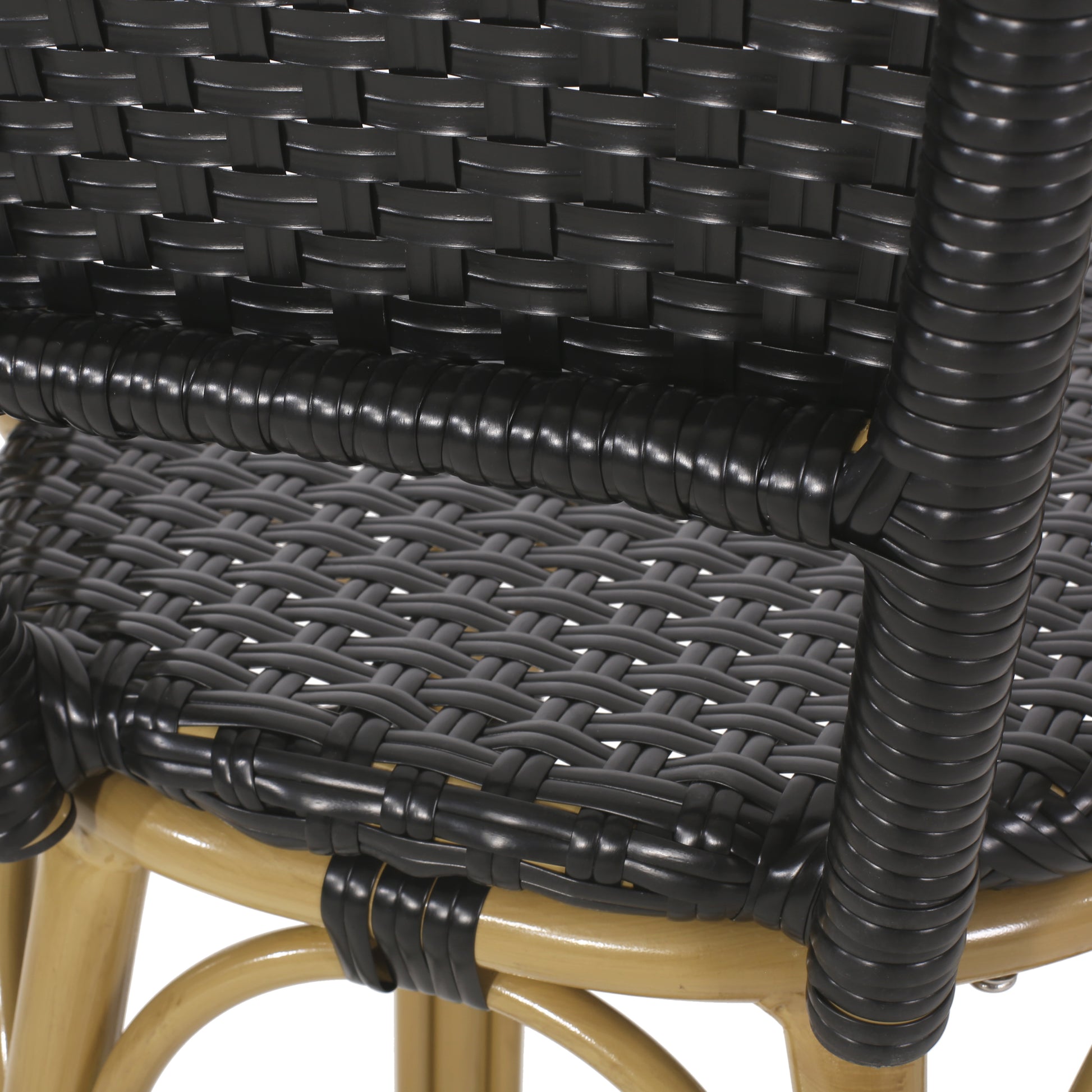 Closeup of black rattan weave on a tan wicker chair frame ideal for outdoor furniture