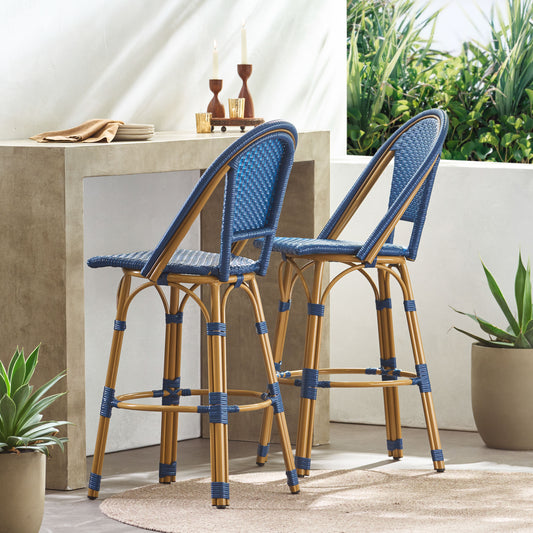 Two blue woven rattan bar stools with golden bamboo frames for outdoor seating