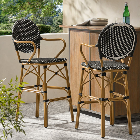 Two black and white patterned wicker bar stools with gold metal frames on an outdoor patio