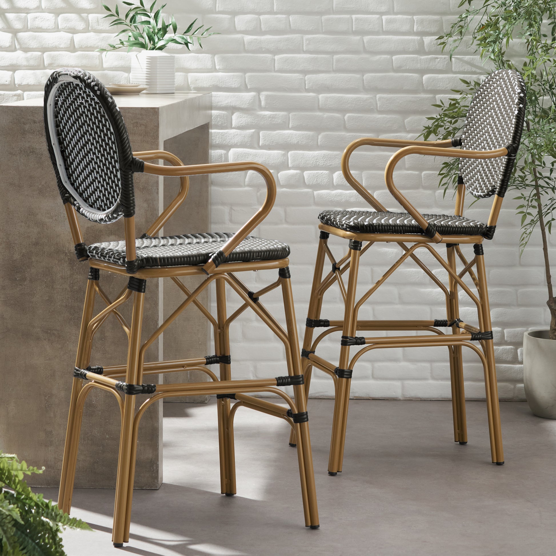 Two elegant rattan bar stools with black and white woven seats and backs on gold metal frames