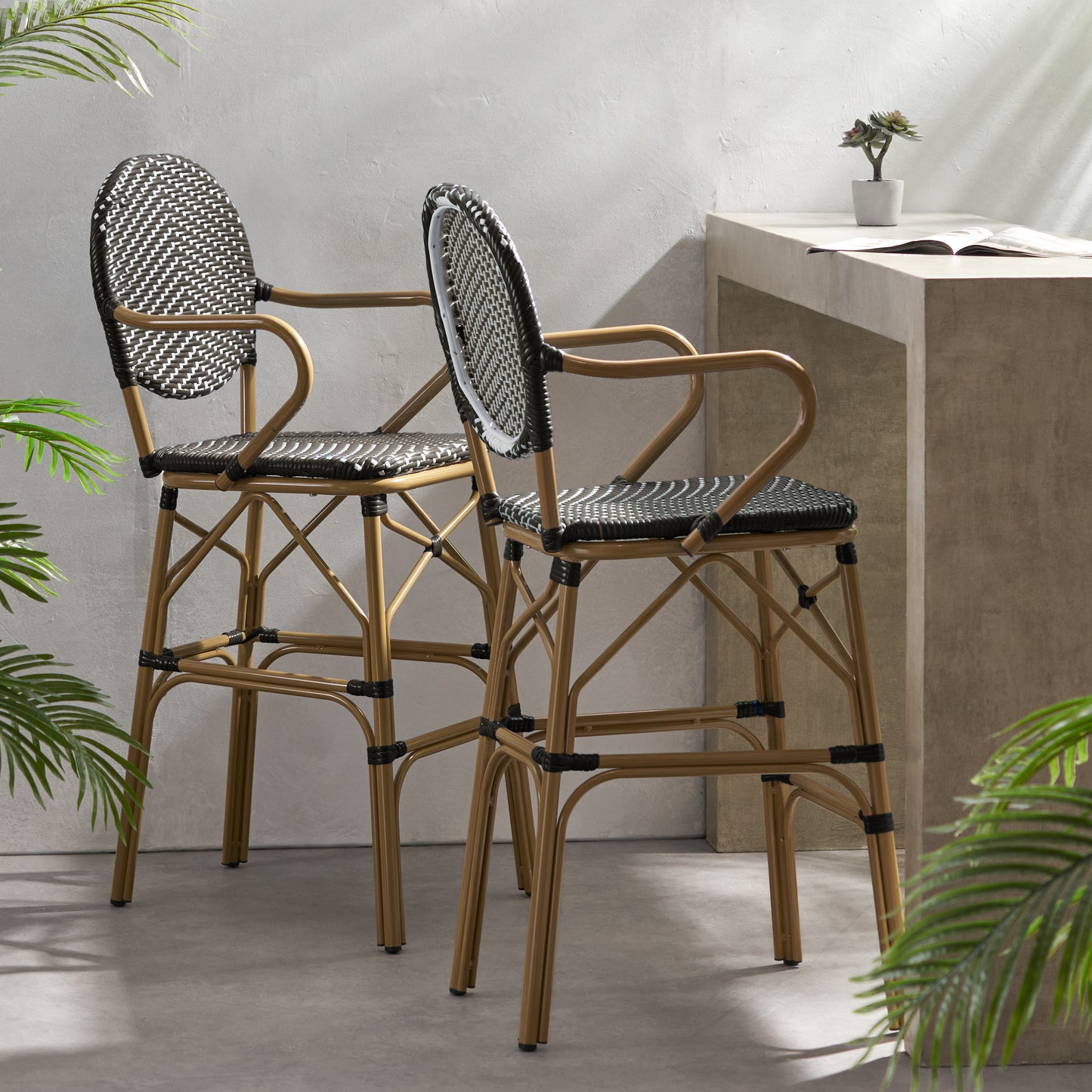 Two brown rattan bar stools with black woven seats and backs designed for outdoor seating