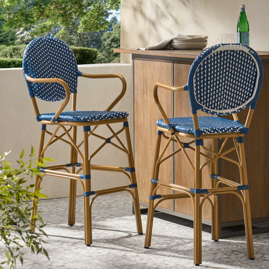 Two blue and white wicker bar stools with gold frames on a patterned patio