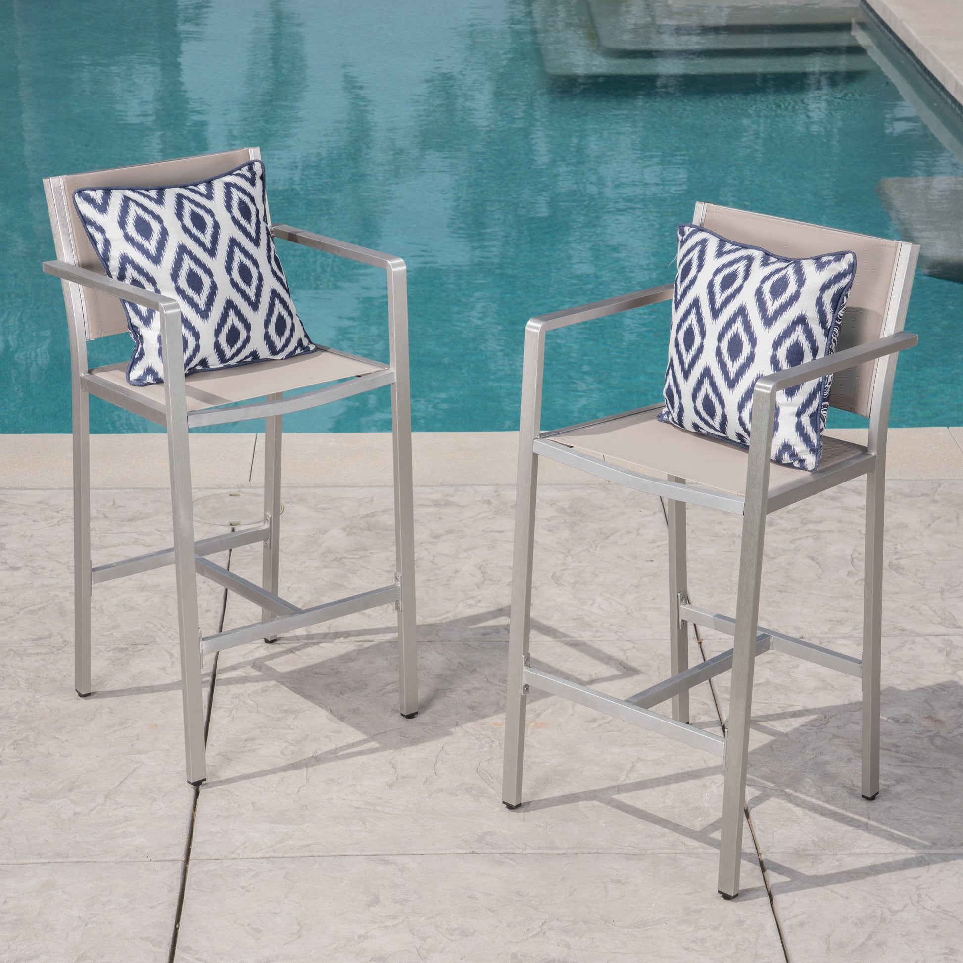 Pair of modern silver outdoor bar stools with taupe fabric and blue diamond pattern pillows
