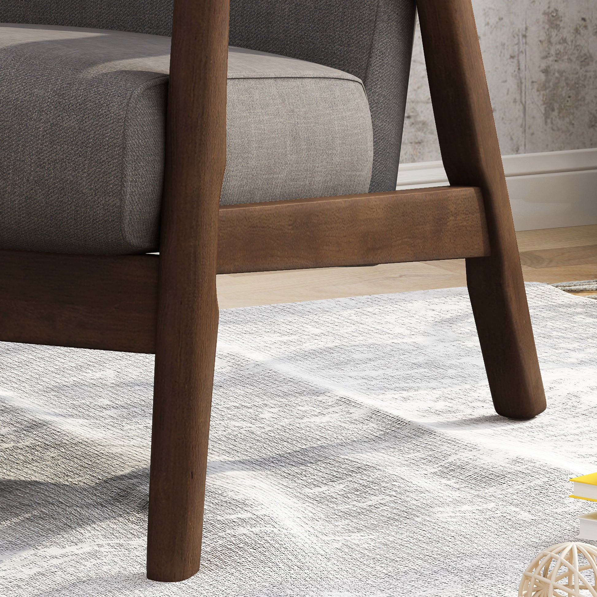 Dark brown wooden legs of a modern upholstered armchair on a textured rug