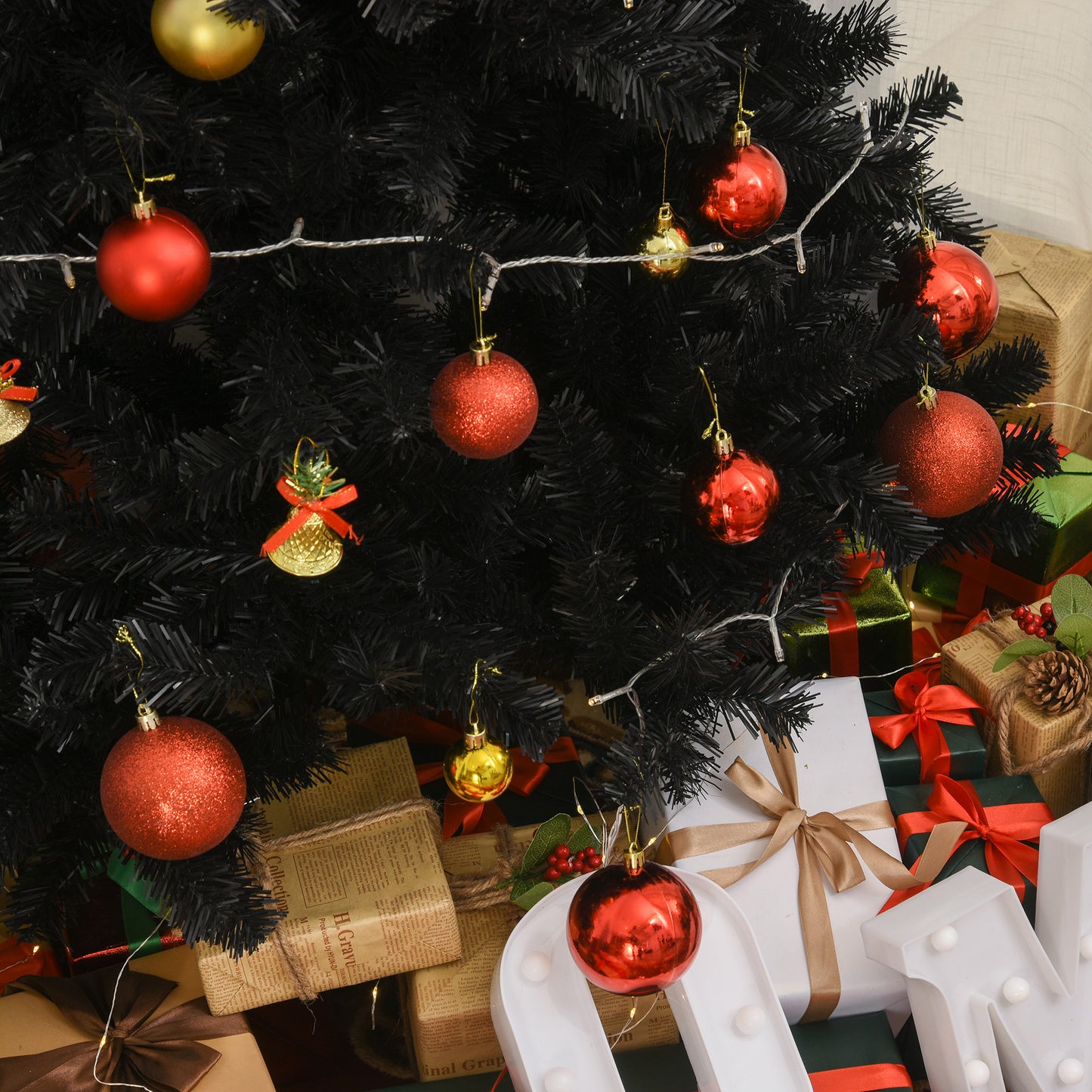 Red glitter Christmas ornament hanging from a black tree with string lights