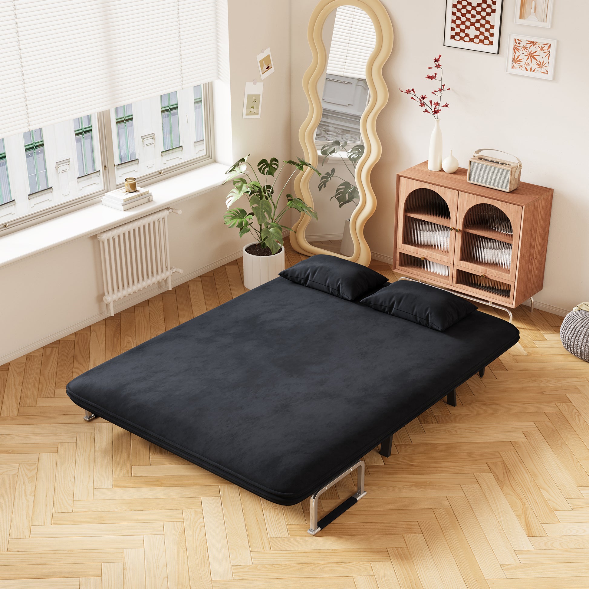 Black velvet sofa bed with two pillows perfect for small spaces