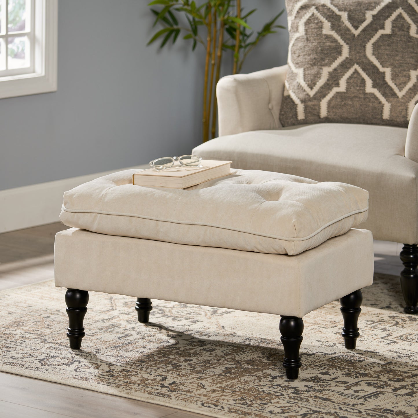 Tufted beige fabric ottoman with dark wood legs perfect as a footrest