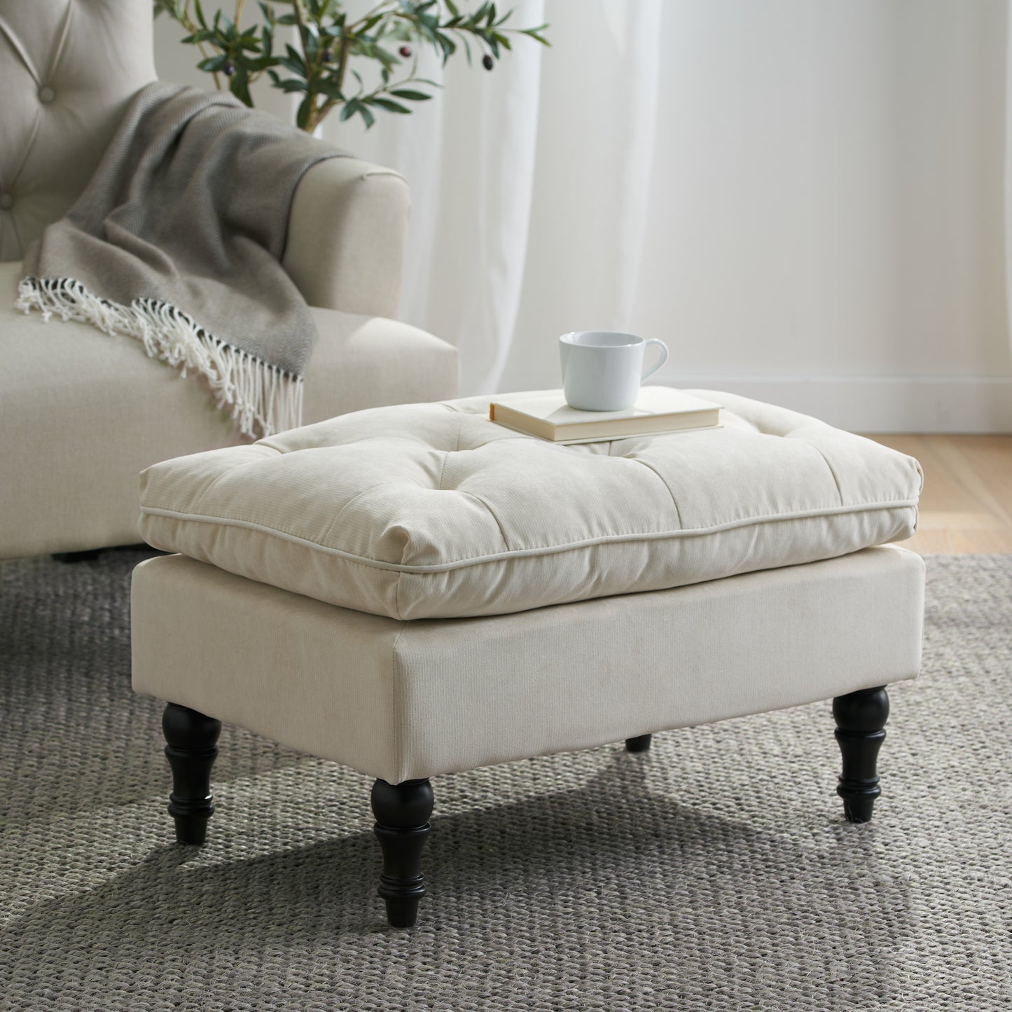 Tufted linen ottoman with dark wood legs perfect for a living room