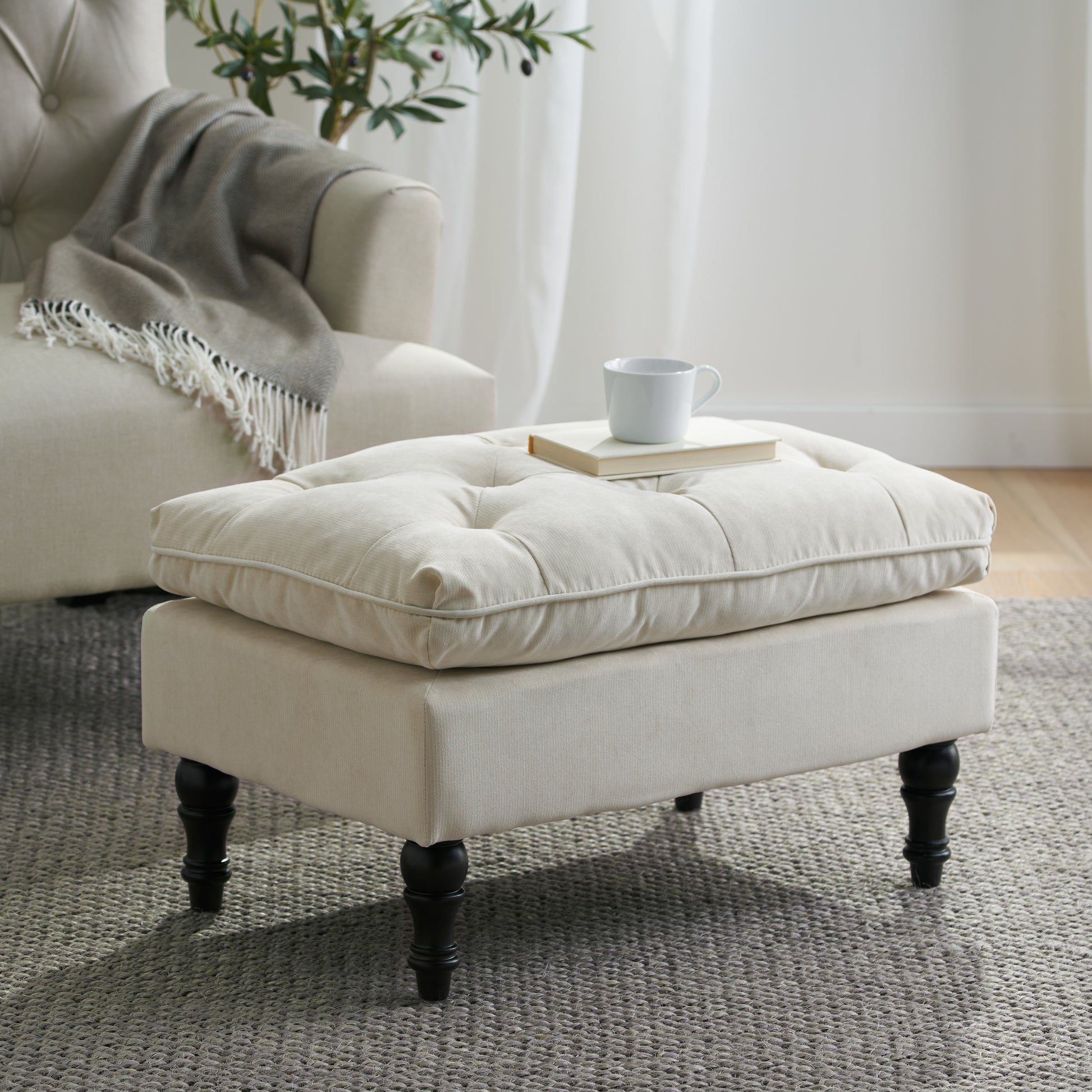 Tufted linen ottoman with dark wood legs perfect for a living room