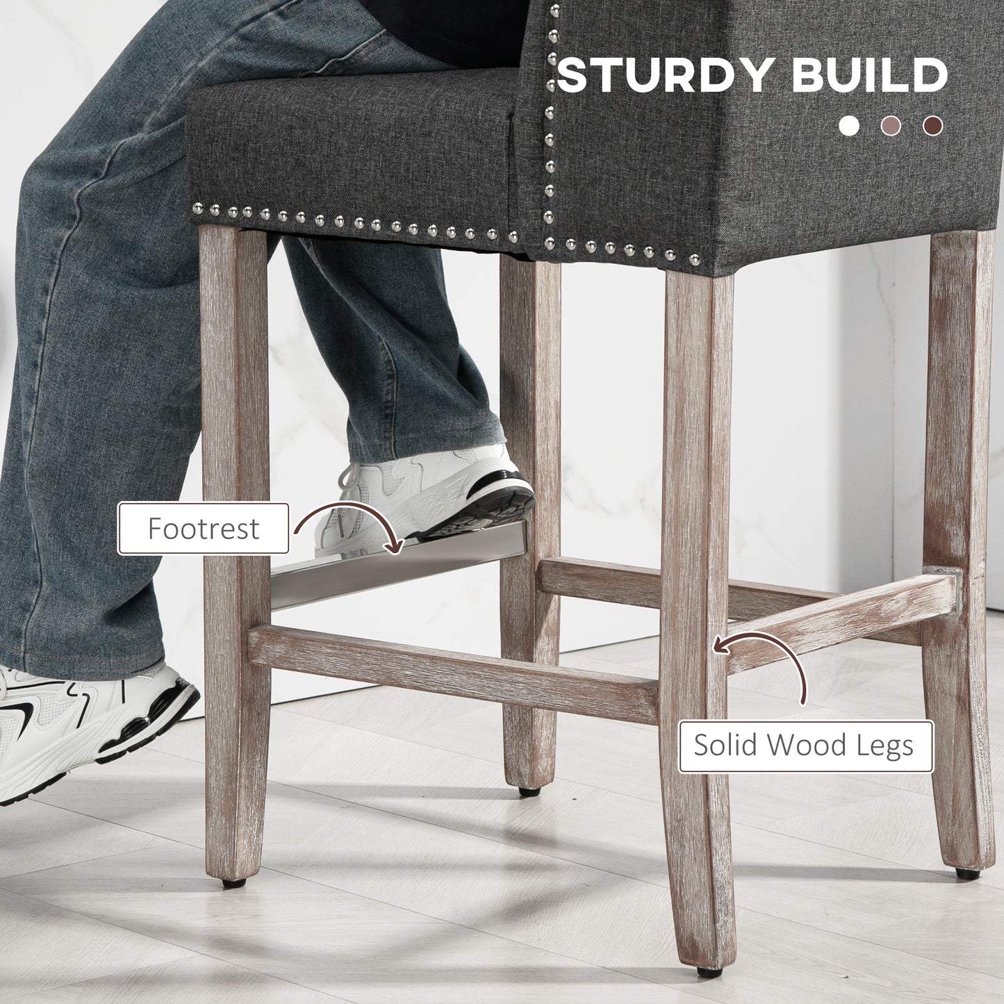 Dark grey upholstered bar stool with nailhead trim and solid wood legs
