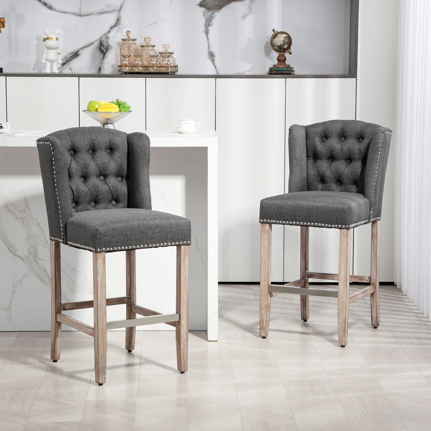 Tufted dark grey fabric bar stool with silver nailhead trim and natural wood legs