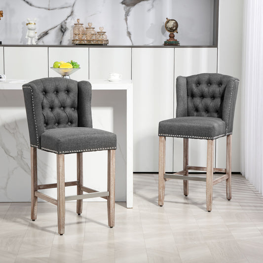 Tufted dark grey fabric bar stool with silver nailhead trim and natural wood legs