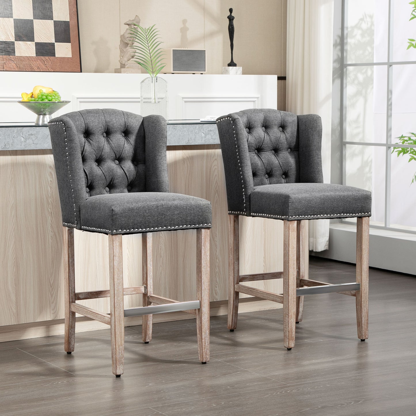 Two grey tufted upholstered bar stools with nailhead trim and wooden legs