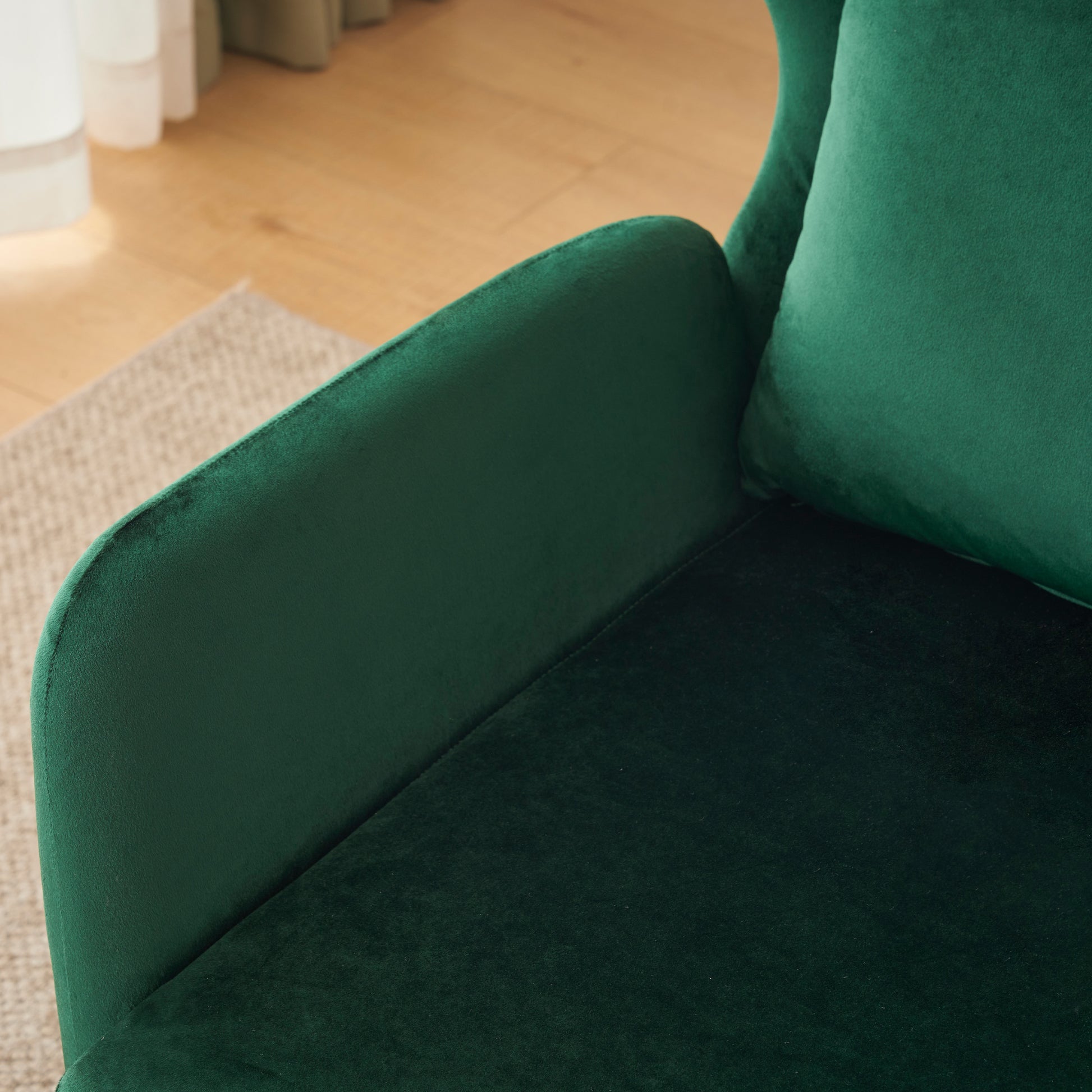 Closeup of a plush emerald green velvet armchairs armrest and cushion