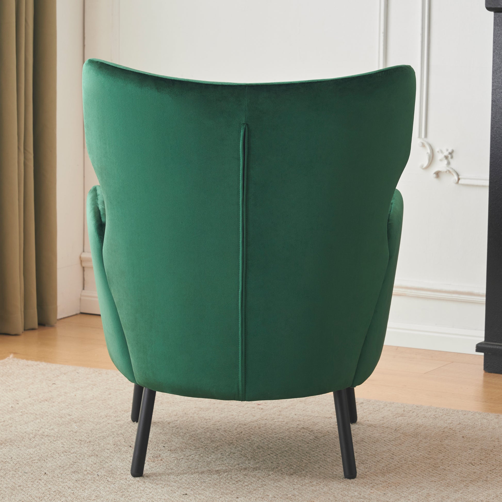 Emerald green velvet accent chair with sculpted back and tapered legs