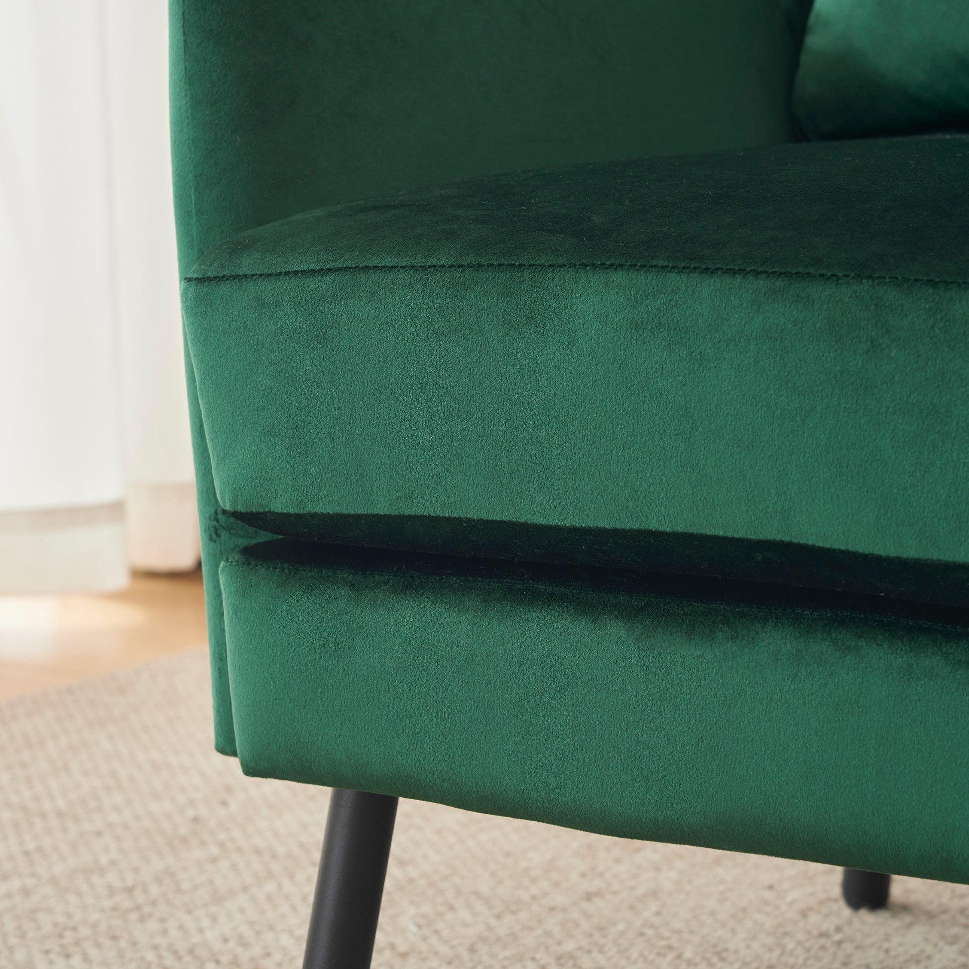 Deep green velvet armchair detail with black tapered legs