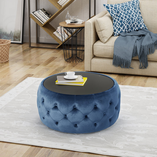 Blue velvet tufted ottoman with dark round top and books