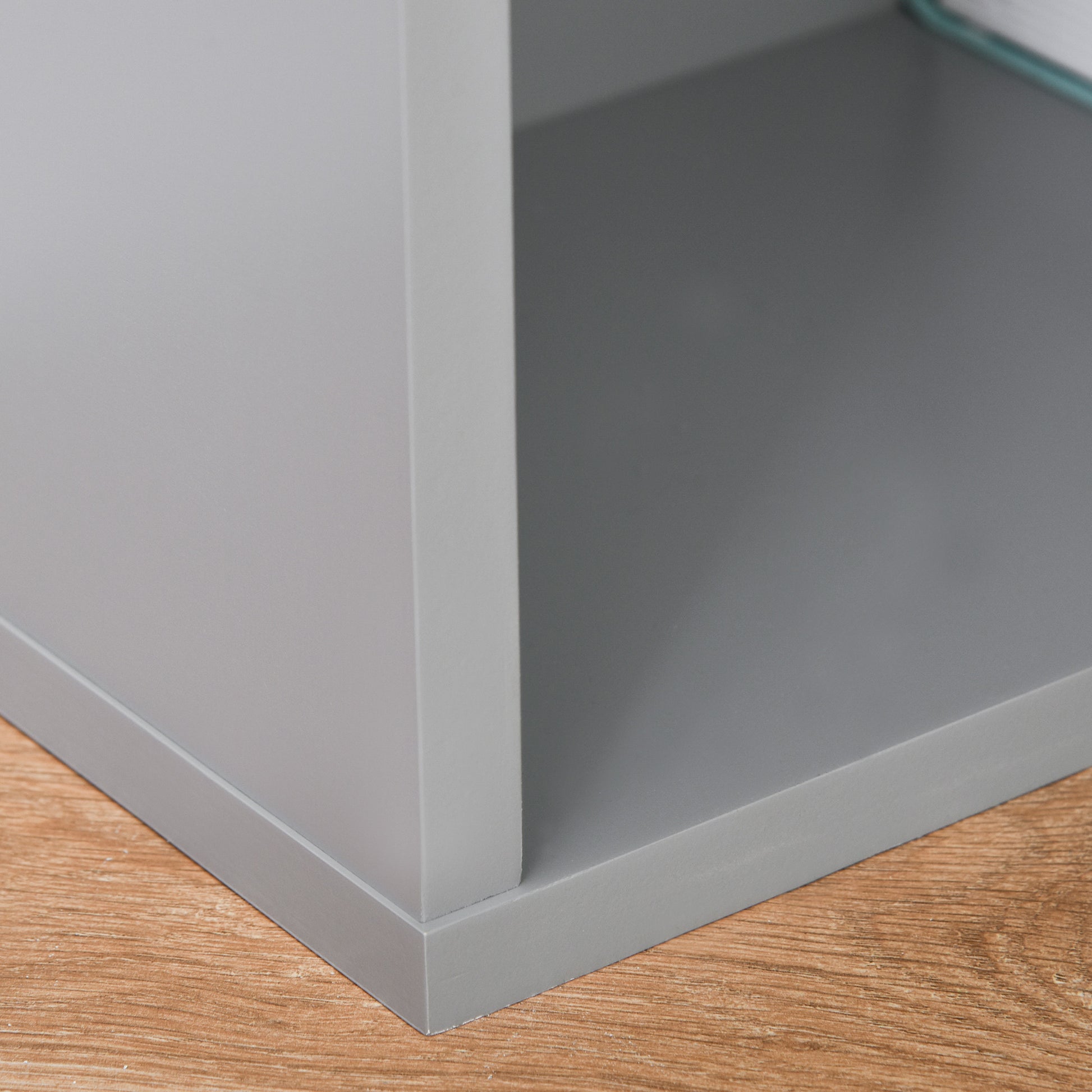 Closeup of a modern grey cube shelf unit corner with a wood grain floor