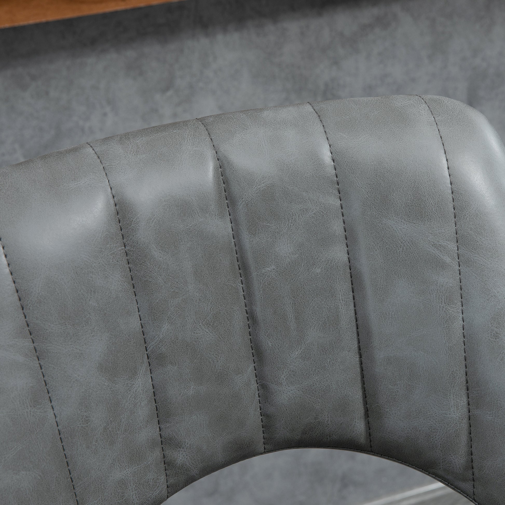 Closeup of grey faux leather tufted chair back with visible stitching