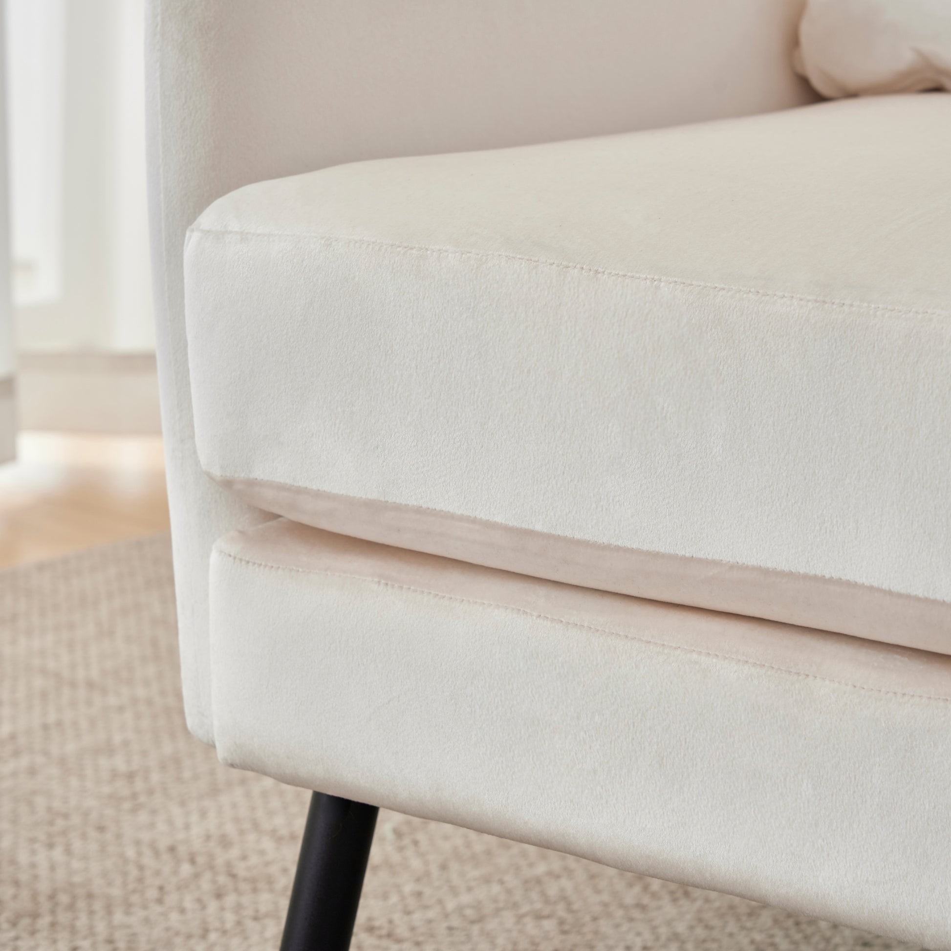 Cream velvet accent chair with stitched detailing on armrest and black metal legs
