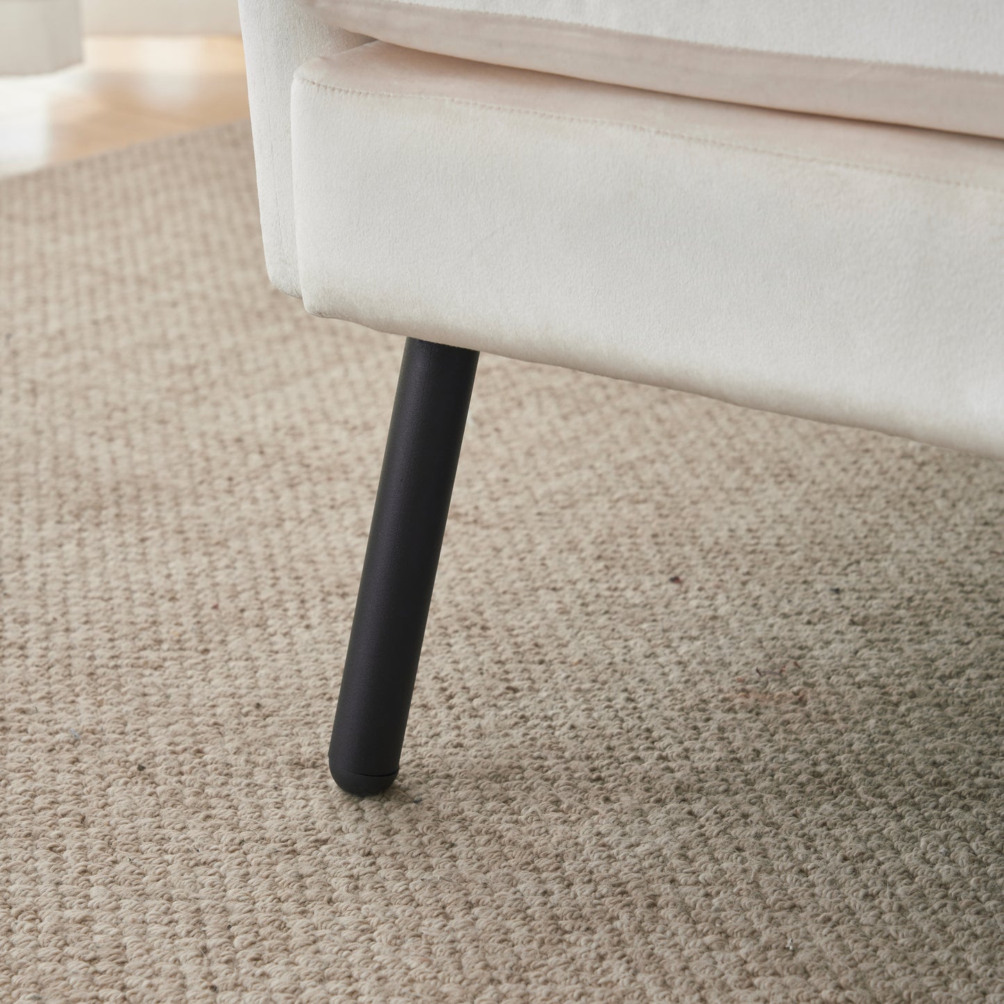 Cream velvet armchair leg on textured beige rug