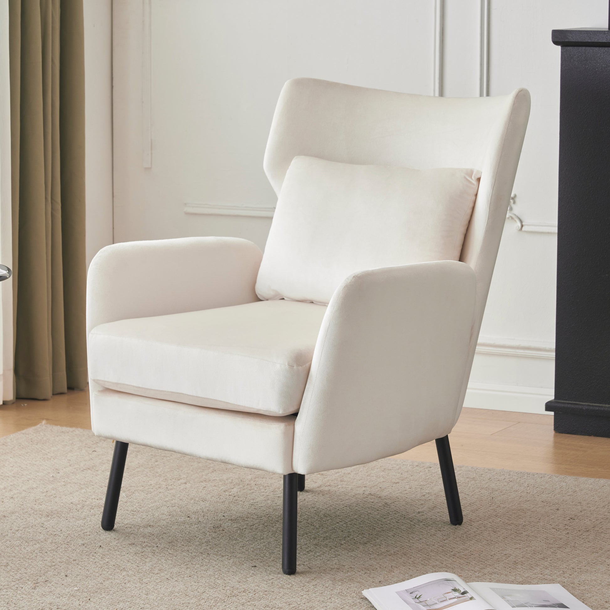 Cream velvet accent chair with slender black legs and a matching lumbar pillow