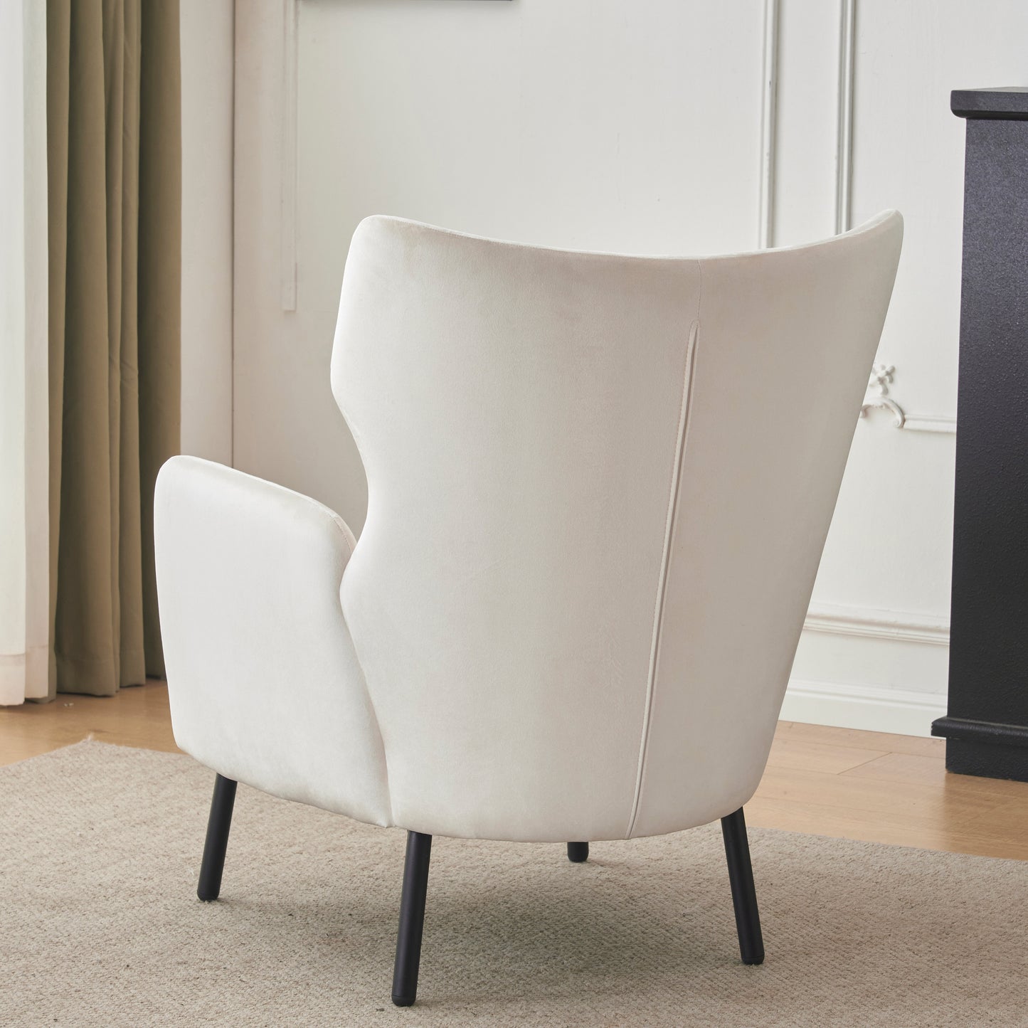 Rear view of a cream velvet accent chair with black tapered legs
