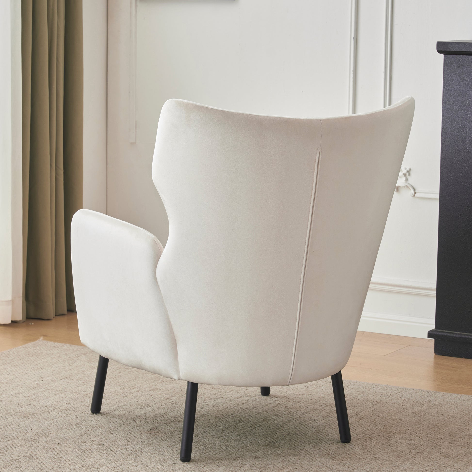 Rear view of a cream velvet accent chair with black tapered legs