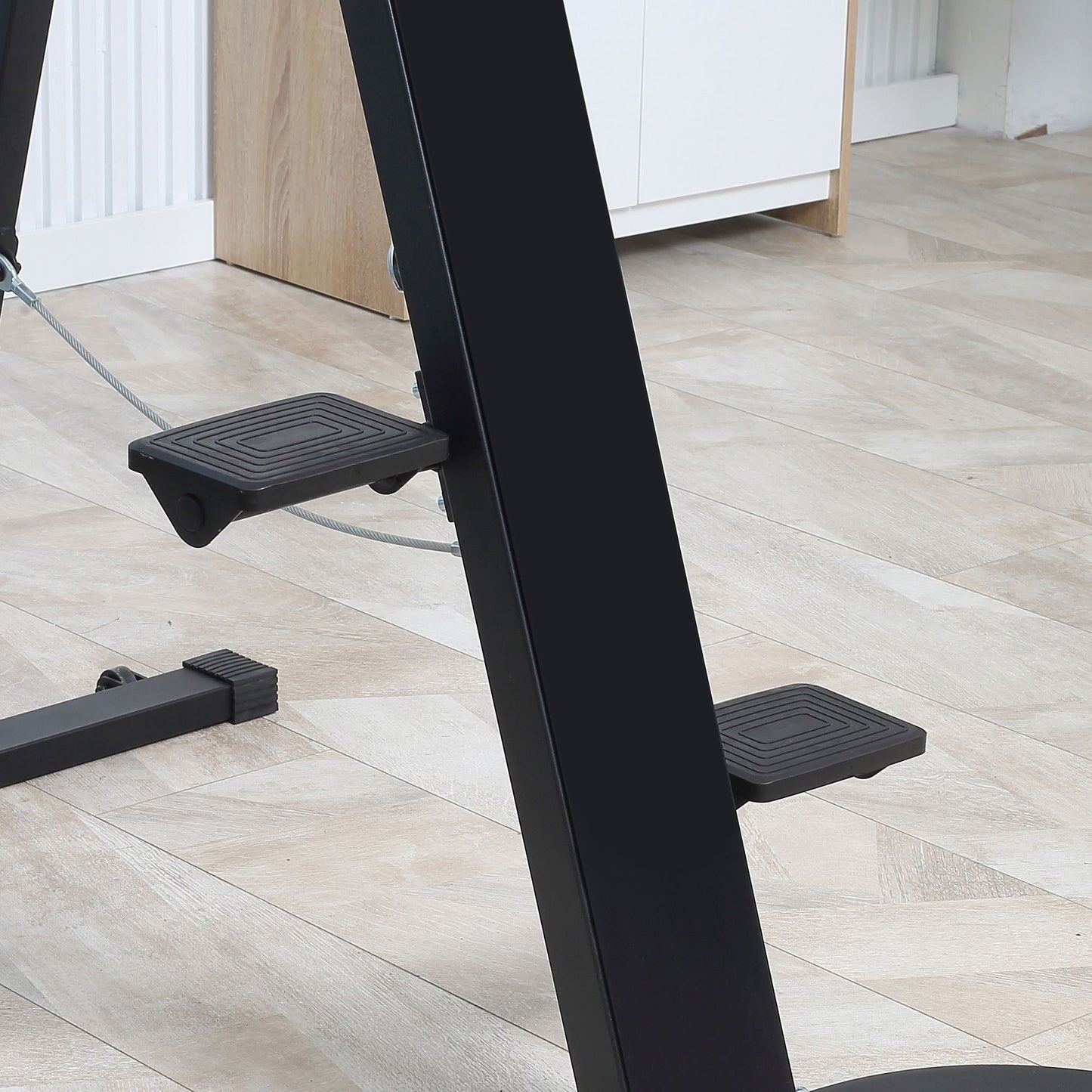 Black textured foot pedals on a metal exercise machine frame