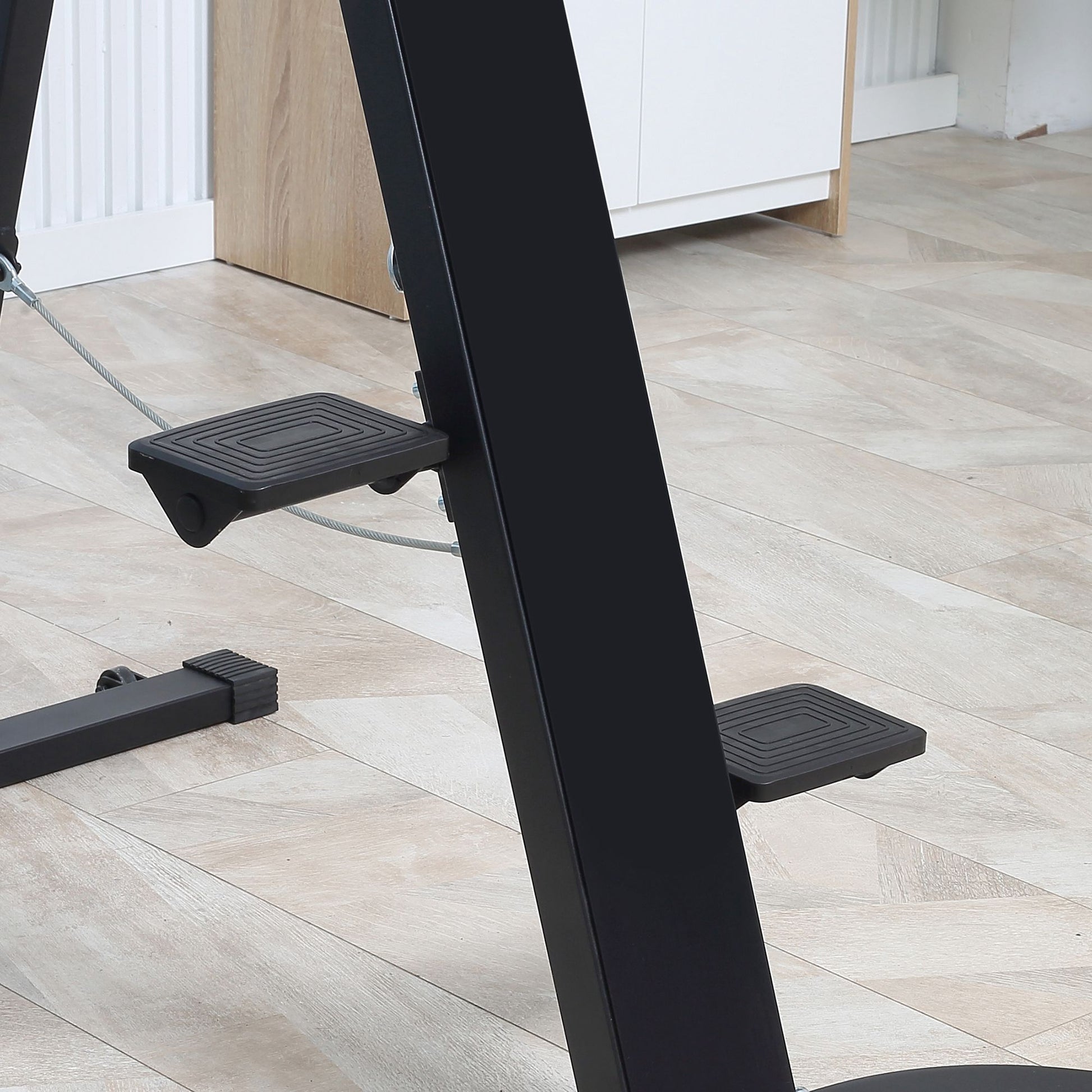 Black textured foot pedals on a metal exercise machine frame
