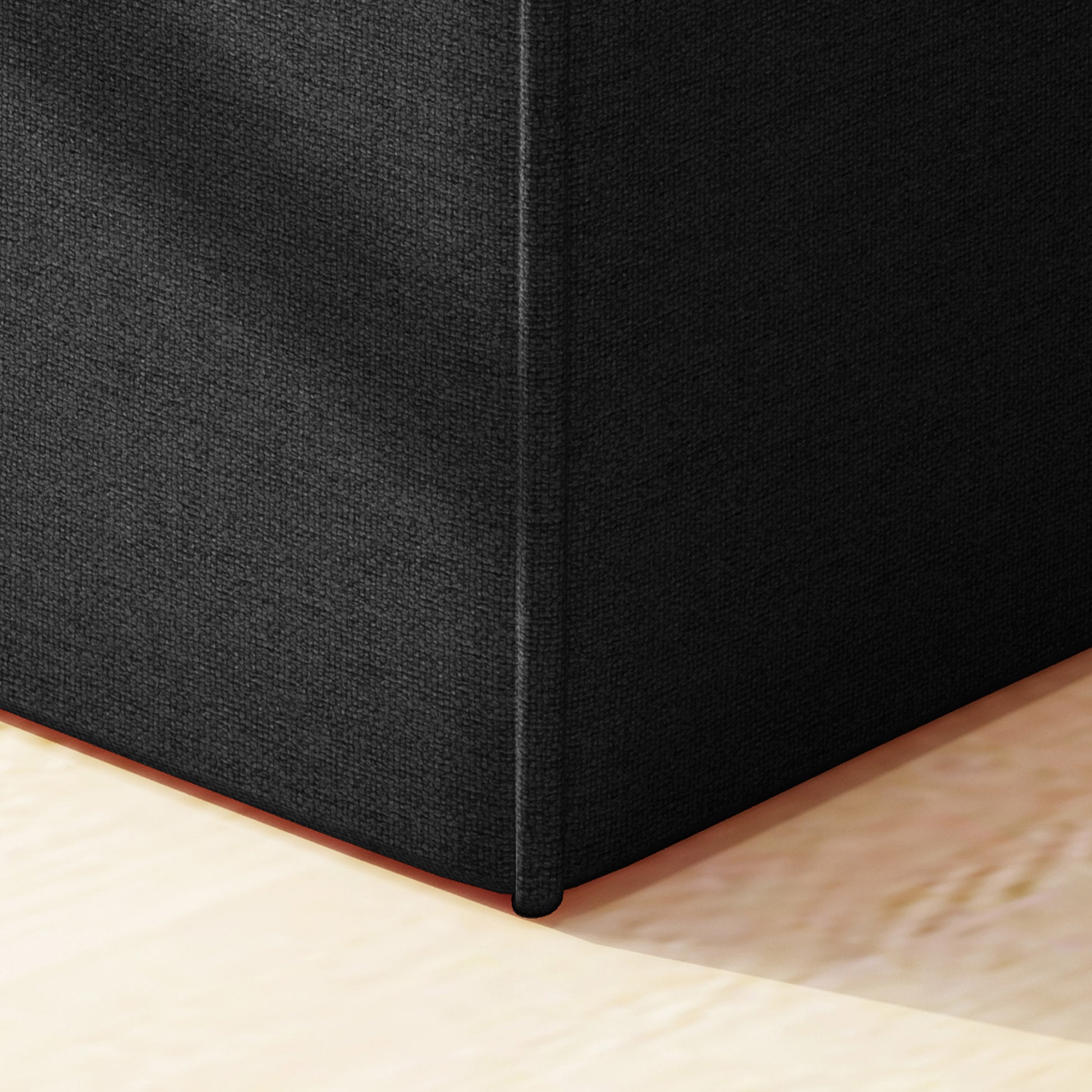 Black upholstered ottoman corner with textured fabric