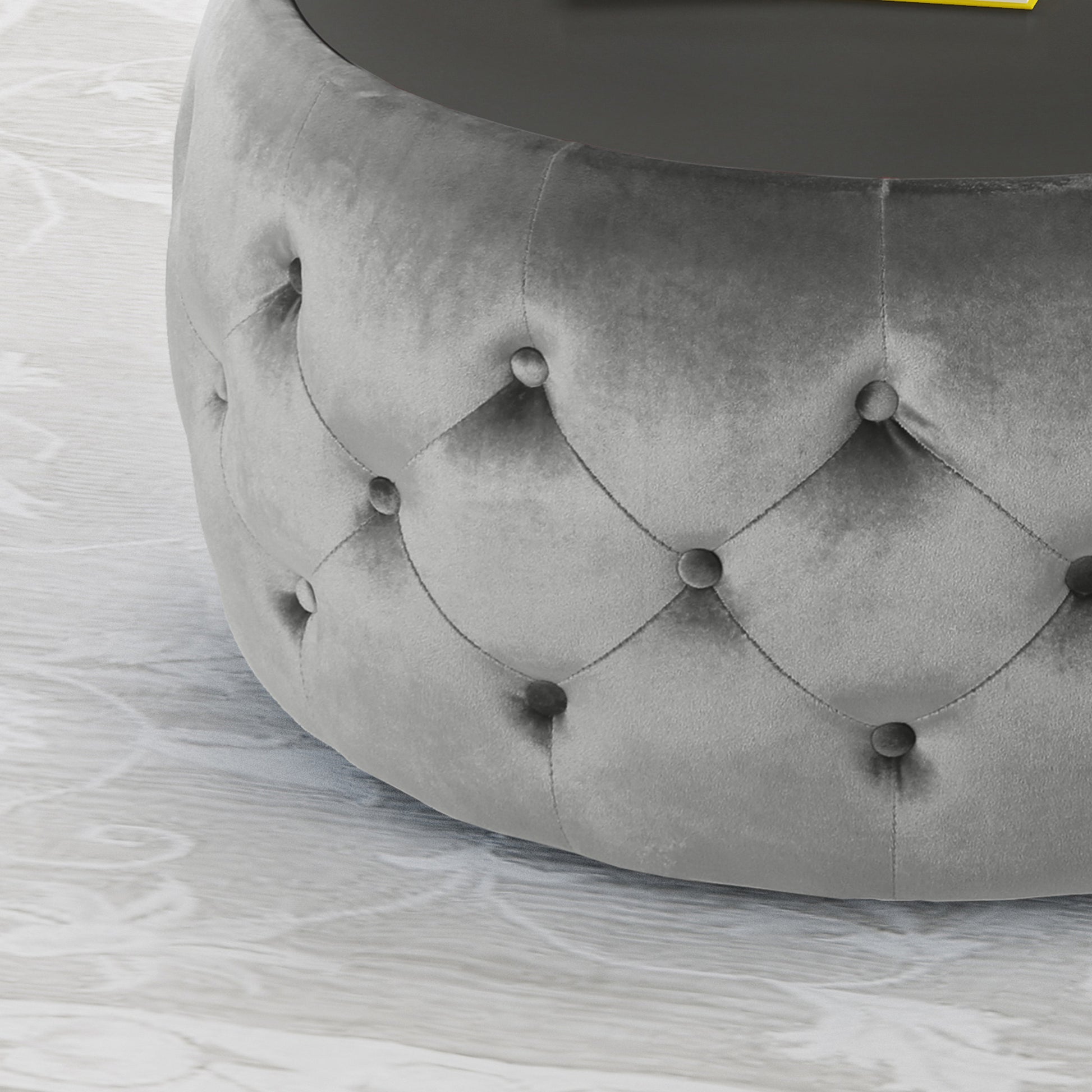 Gray velvet tufted ottoman with a circular glass top
