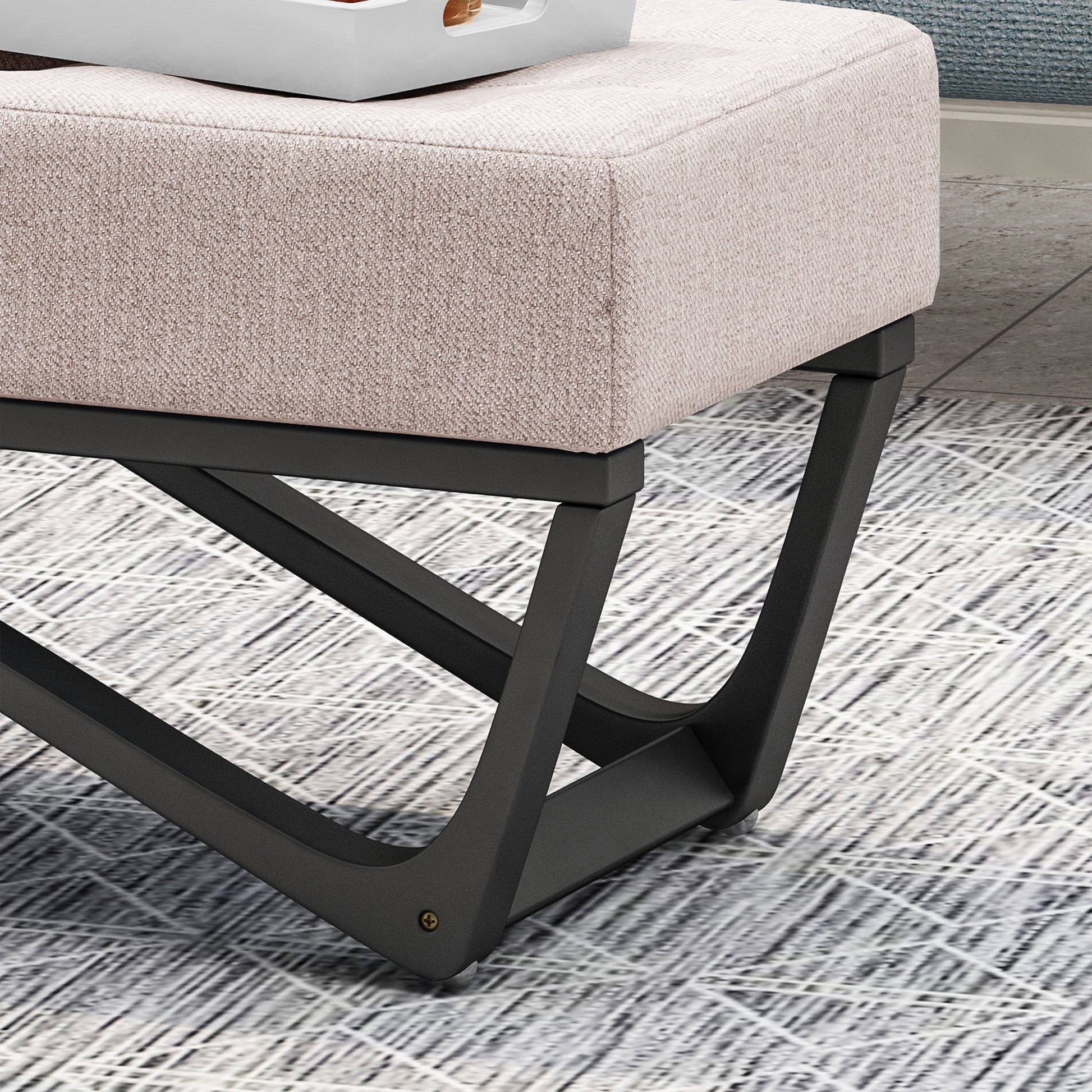 Textured beige fabric ottoman with a modern black metal base and geometric legs