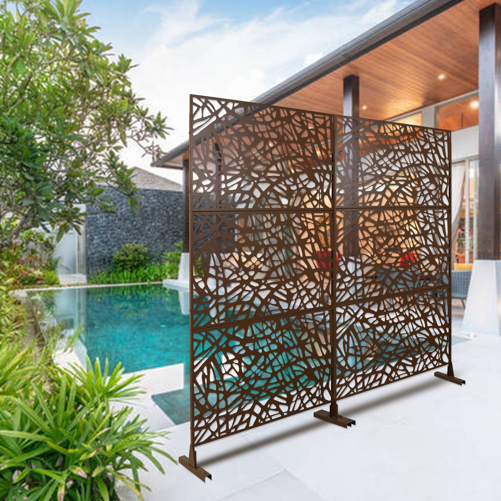 Brown metal decorative garden screen with intricate leaflike cutouts providing privacy poolside
