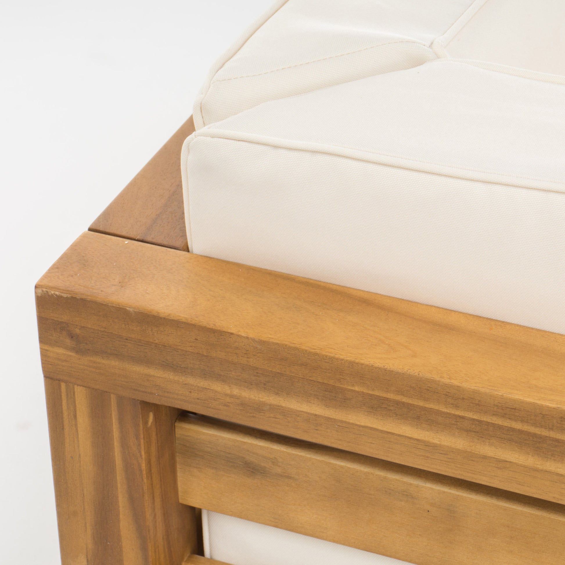 Closeup of a wooden outdoor sofa armrest with cream cushions highlighting craftsmanship